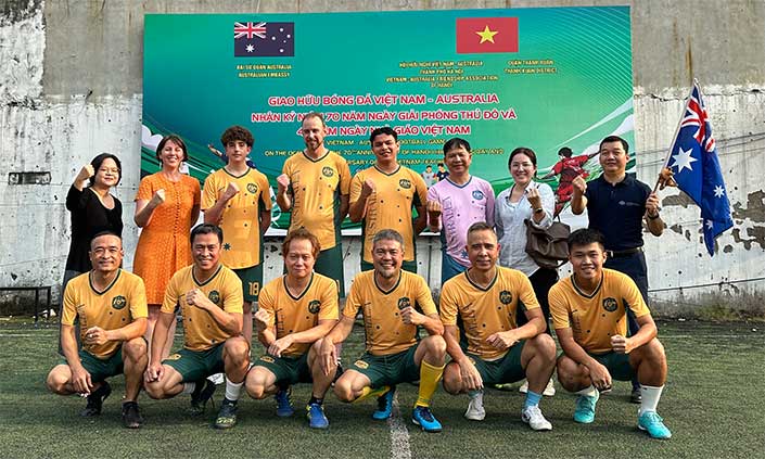 Football team in front of a building with Australian and Vietnamese flags on a sign 