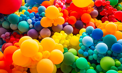 Hundreds of balloons of various sizes in clusters of rainbow colours.