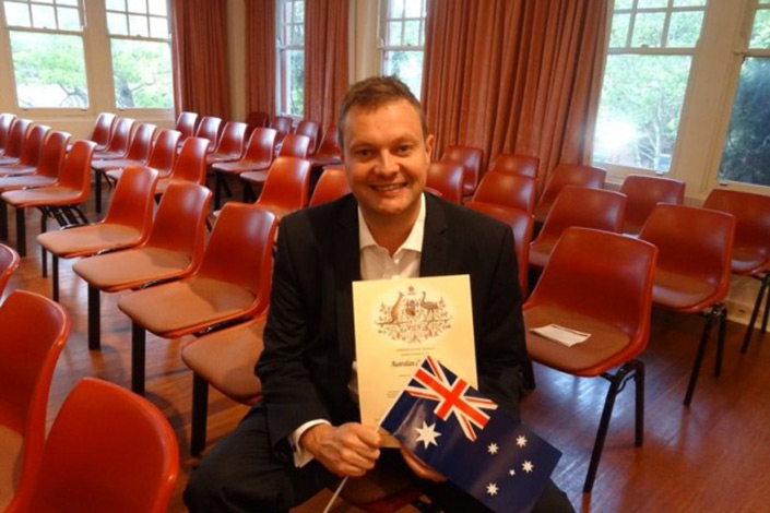 Roger holding Australian flag and certificate