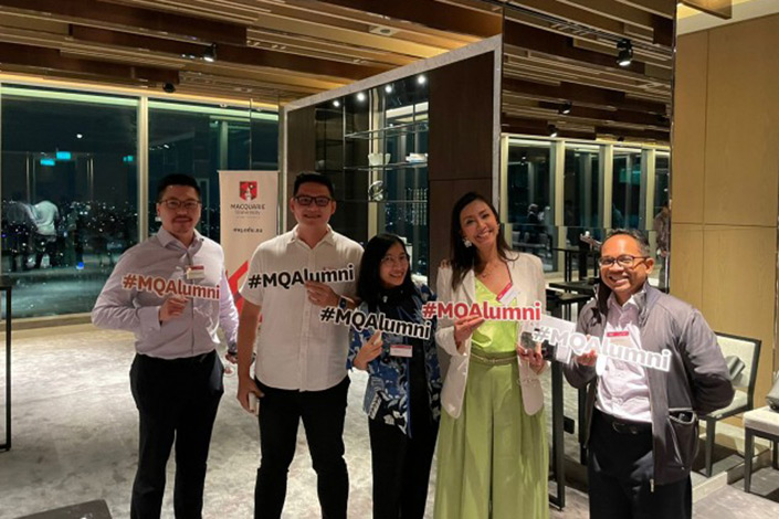 MQ alumni in Indonesia holding an '#MQ Alumni' sign