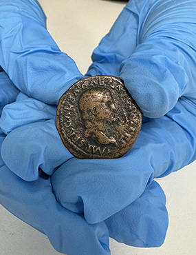 hands holding an ancient Roman coin