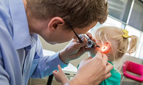 Health professional checking childs ear