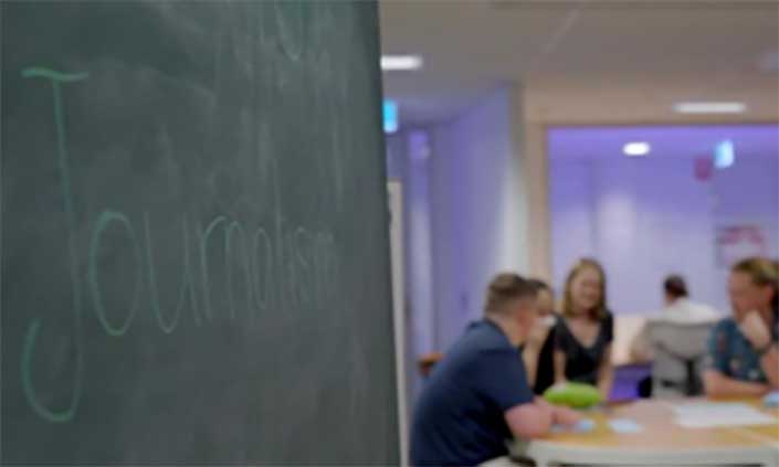 A chalkboard with 'Journalism' written on it, and students in the background