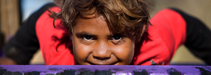 An Indigenous child leaning on a tyre