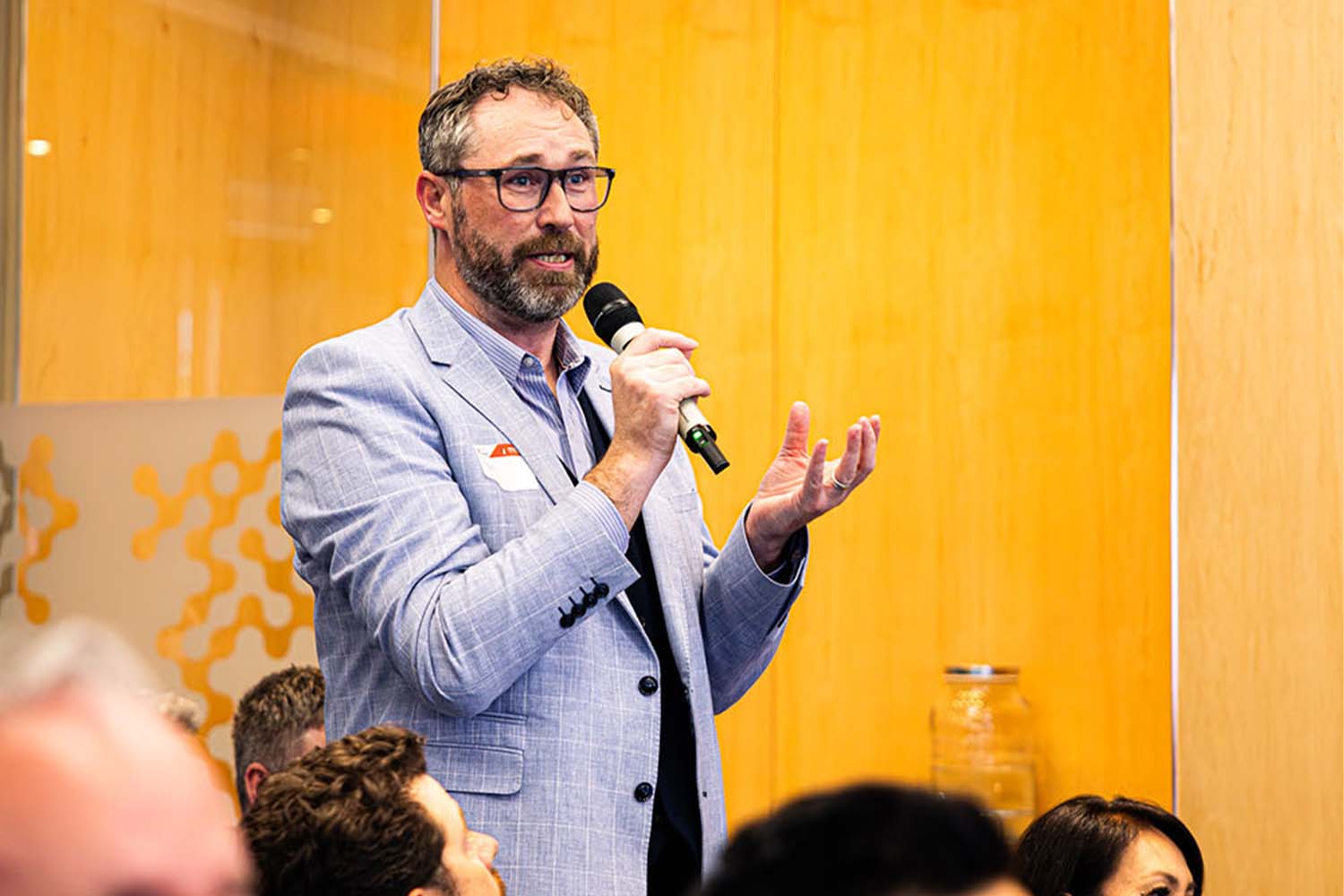 A person in a suit holding a microphone and asking a question at an event.