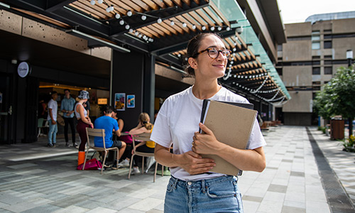 Student holding a book in central courtyard