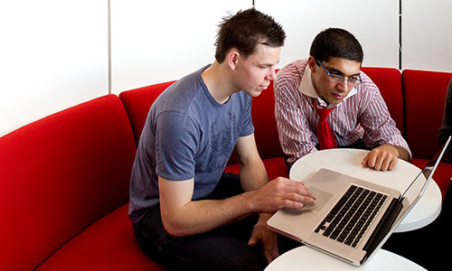 Two students in a Library study space, looking at a laptop.