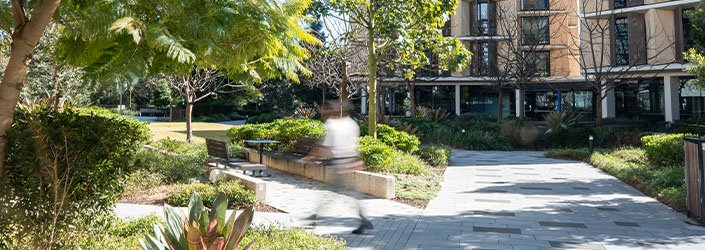 A blurred person walking on the Macquarie University campus.