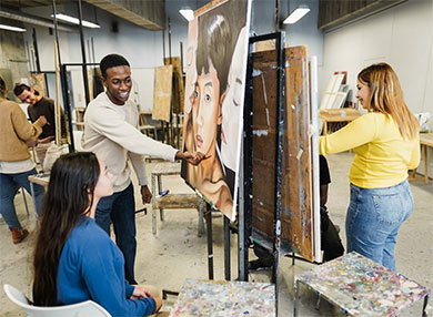 Several students painting inside an art room at a University class