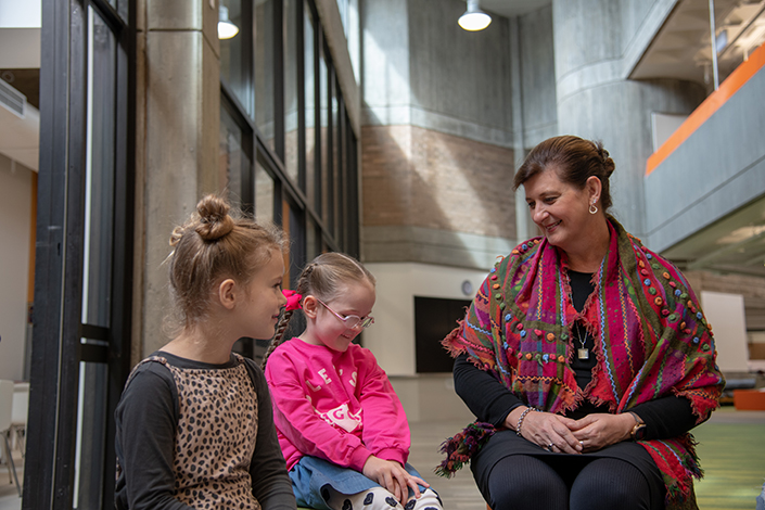 Stephanie McConnell sitting and smiling at two young female students