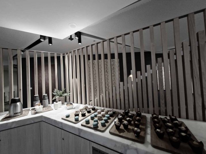 A kitchen bench with tea and coffee making facilities and four trays of bite-sized baked goods.