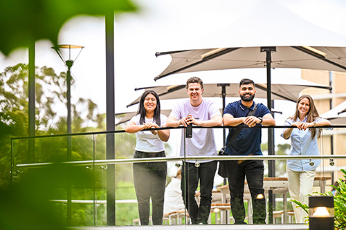 4 students on campus smiling