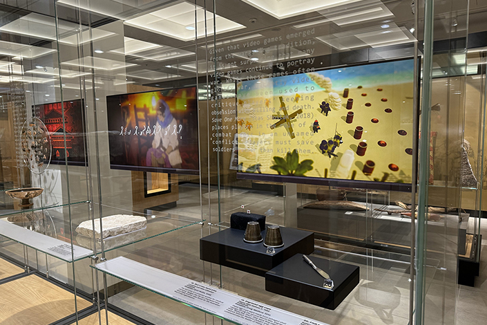 Overview image of museum display featuring video game 'Save One More' and trench art objects