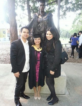 Gunjan graduation photo with family infront of a statue