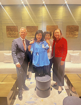 Ines Liu group photo holding a blue macquarie university shirt infront of her