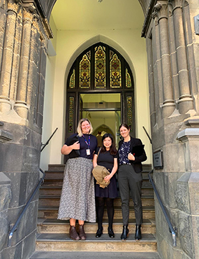 Ines Liu standing outside an old stone church-like building with two companions