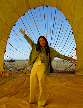 Janice Fung with arms stretched out inside a hot air baloon smiling