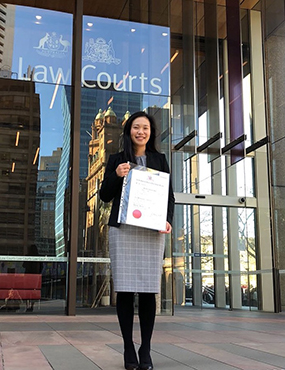 Janice Fung standing infront of a court of law holding an award