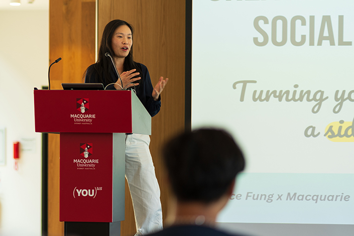 Janice Fung speaking on stage with a presentation at a Macquarie University event