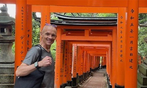 Josh Kidd smiling infront of Japanese Torii gates