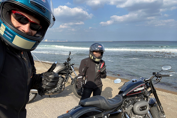 Josh Kidd on the beach with motorbikes and his wife