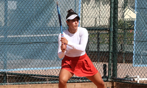 Joya holding a tennis racket ready to return a shot at a tennis court