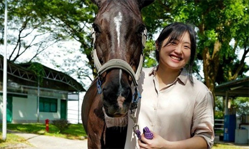 Valerie Teo in a photo holding a horse by the reigns