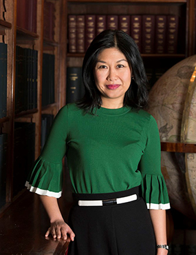 Kathrina Lo posing for a photo in an academic library, wearing a green shirt and black skirt