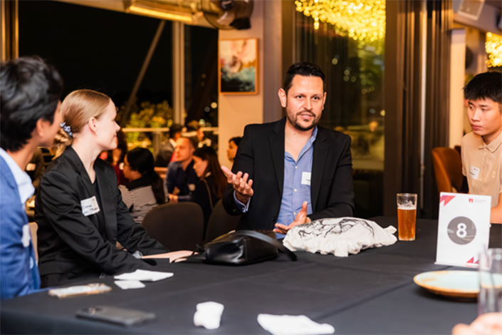 man in a suit tlaking to a group at the Beer with a Boss event