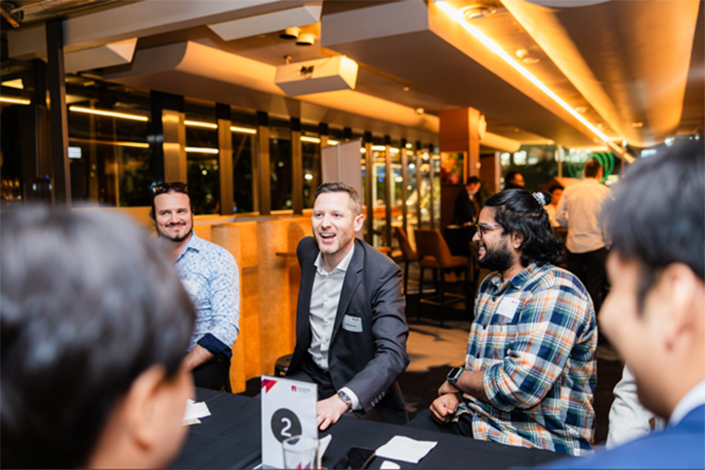 Man in a suit talking to other men at a table