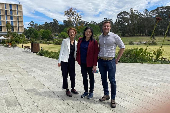 Valerie Teo in a group photo with a man and woman on Macquarie University campus